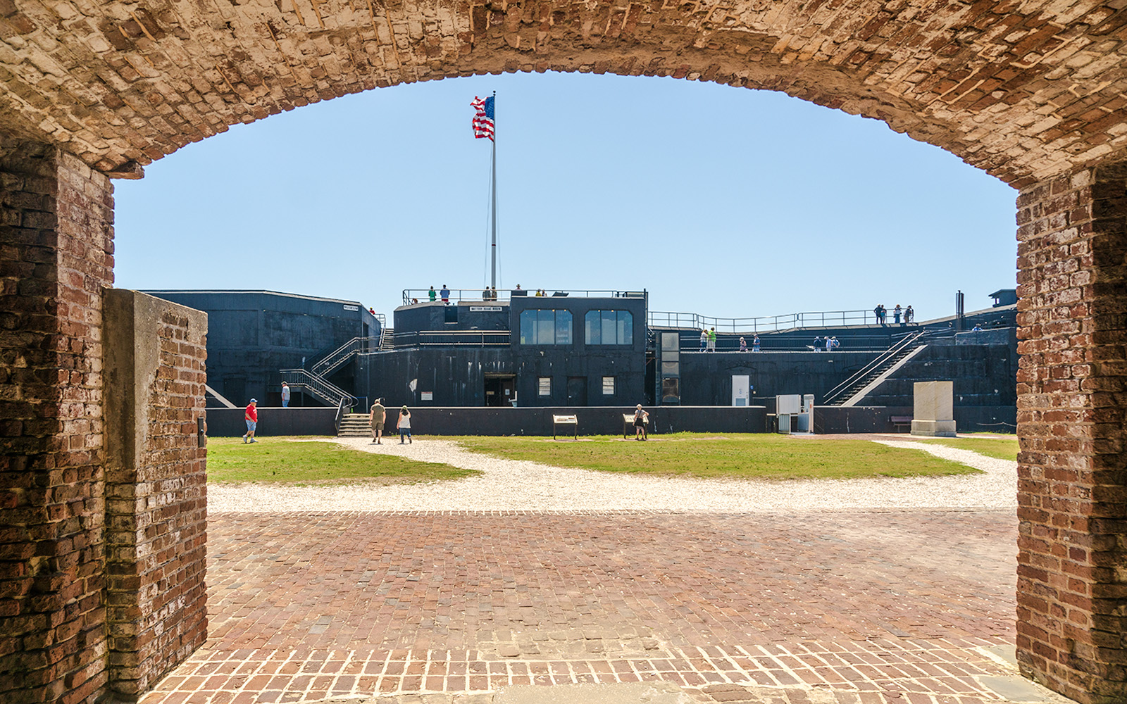 Visitors exploring Fort Sumter National Monument with American flag in view.