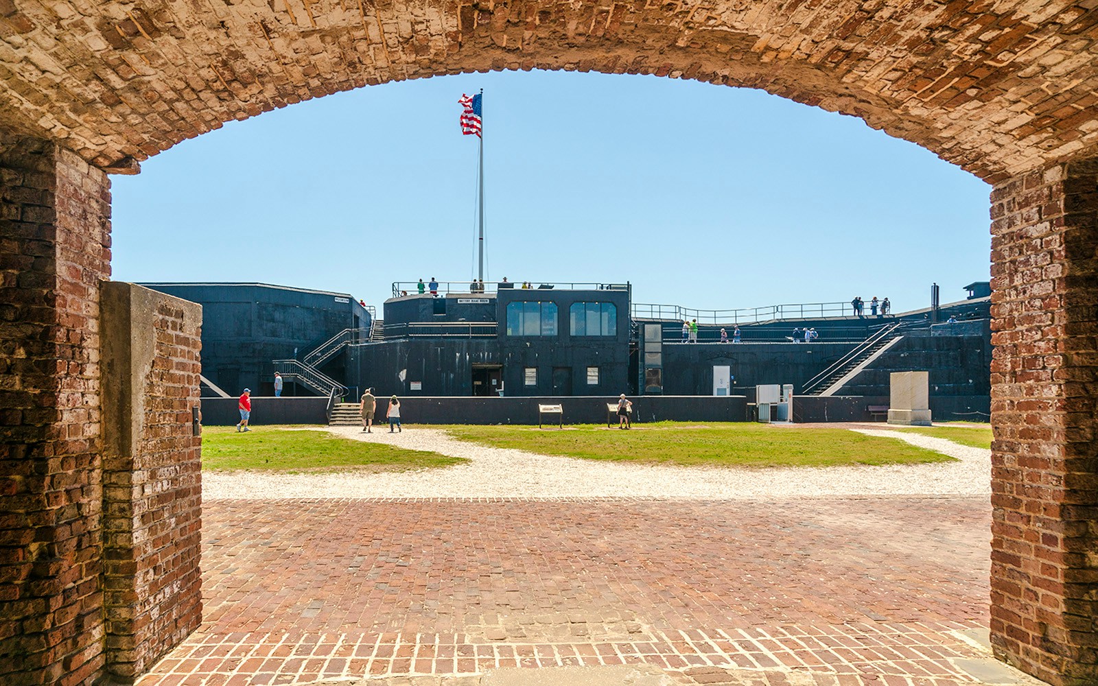 Visitors exploring Fort Sumter National Monument with American flag in view.