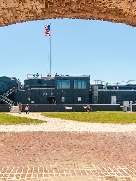 Visitors exploring Fort Sumter National Monument with American flag in view.