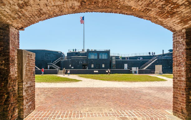 Visitors exploring Fort Sumter National Monument with American flag in view.