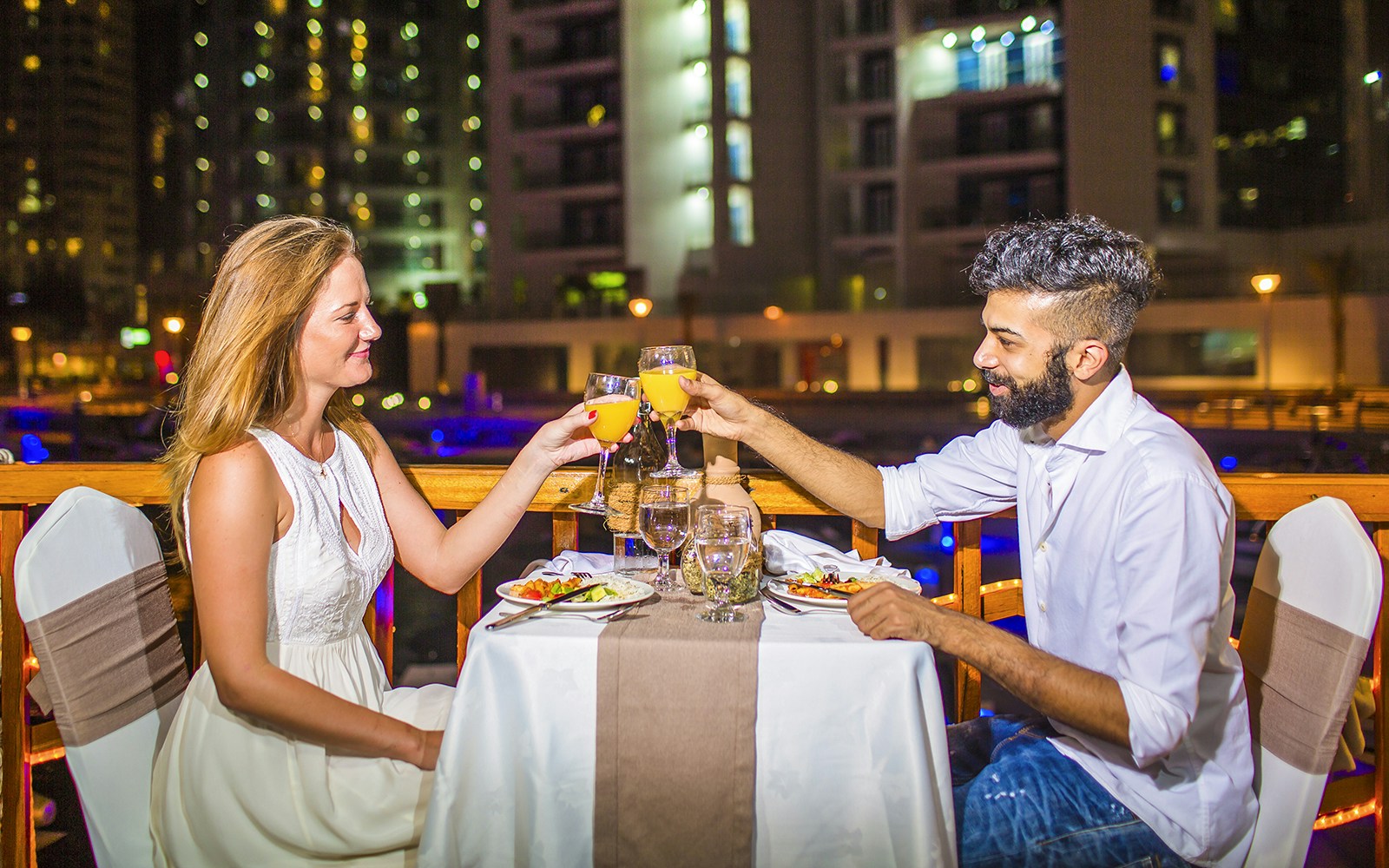 Couple dining on a Dubai Marina dhow cruise with city skyline in the background.