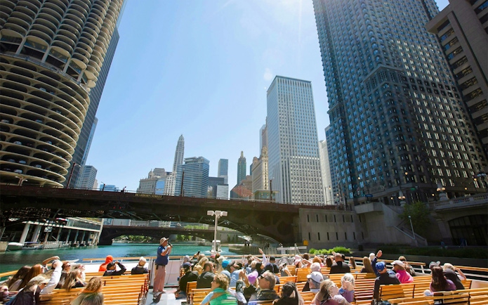 Visitors on Chicago River architecture cruise viewing skyscrapers.