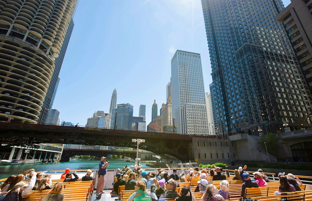 Visitors on Chicago River architecture cruise viewing skyscrapers.