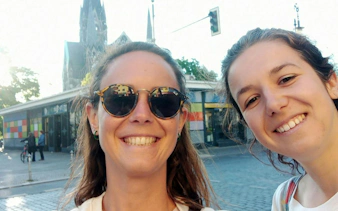 Two people smiling in front of a colorful building in Berlin Kreuzberg.