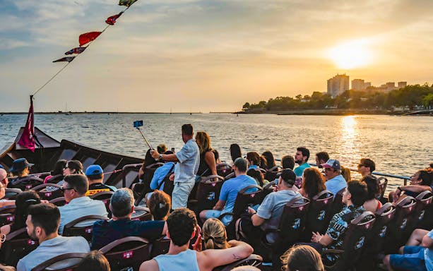 Tourists on a boat enjoying a sunset view over the water.