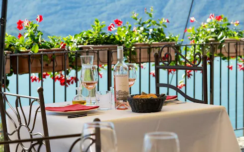 Wine and glasses on a table overlooking Lake Como at Domaso Winery.