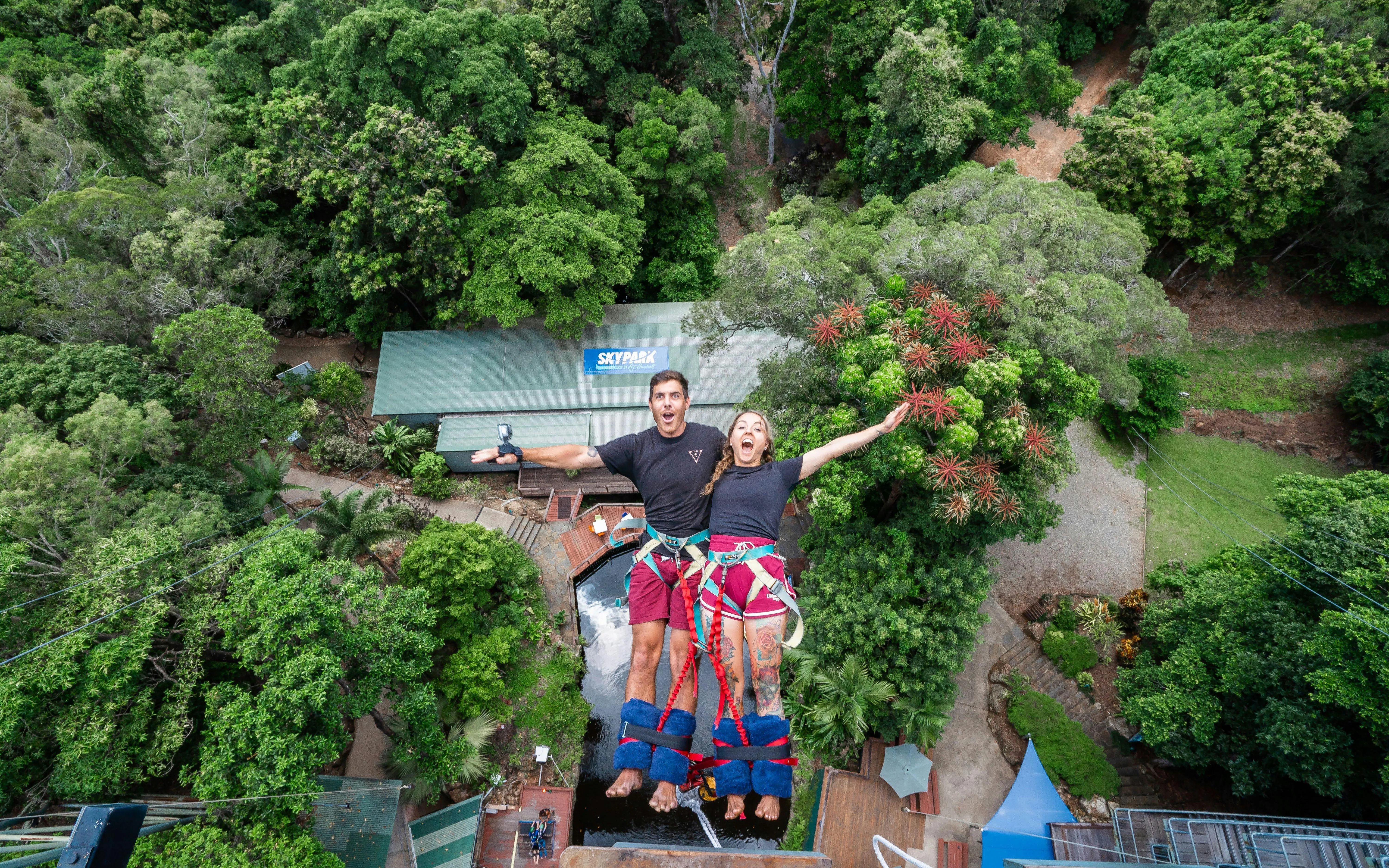 Visitors tandem back diving at Skypark Cairns amidst lush greenery.