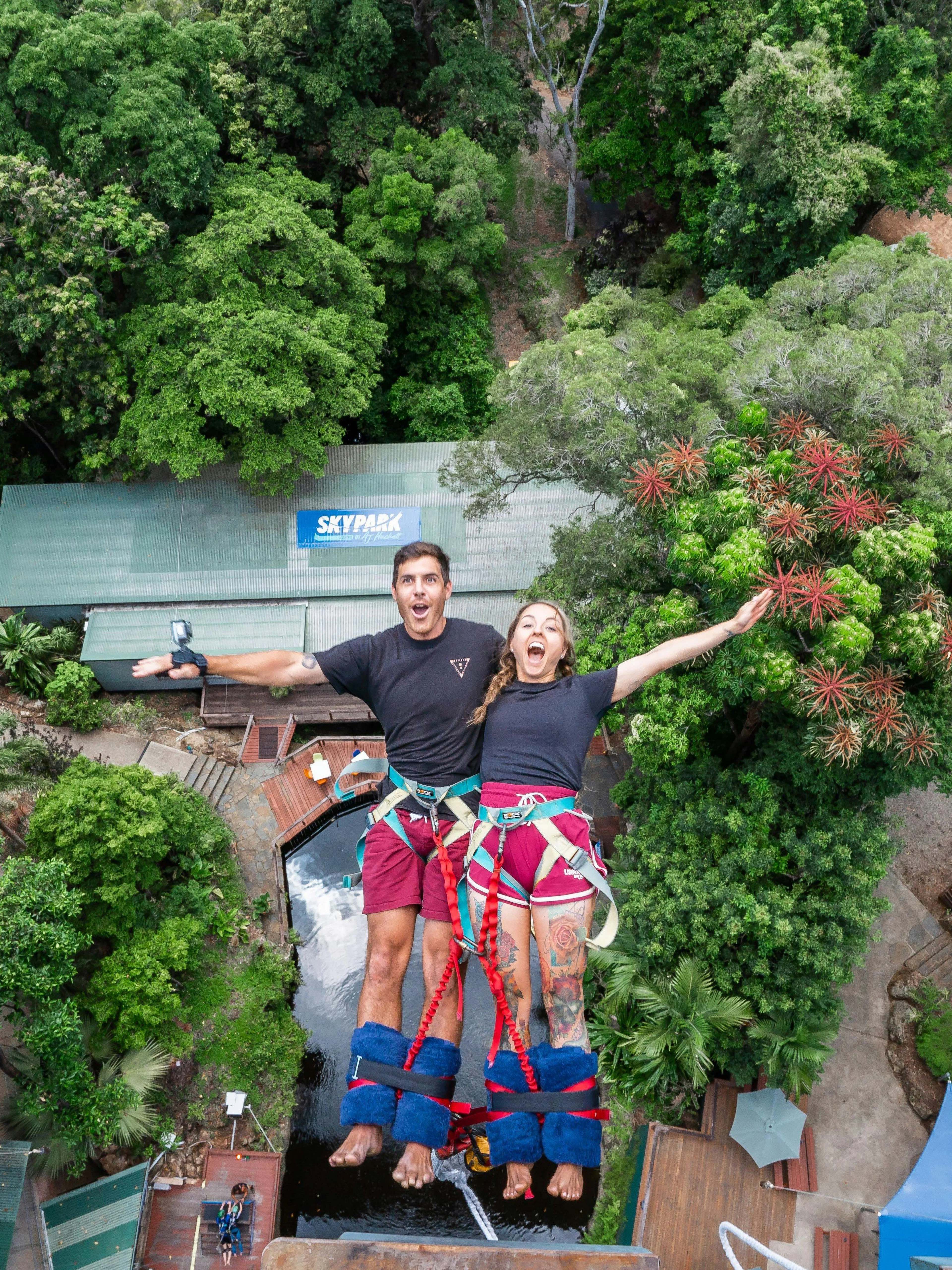 Visitors tandem back diving at Skypark Cairns amidst lush greenery.