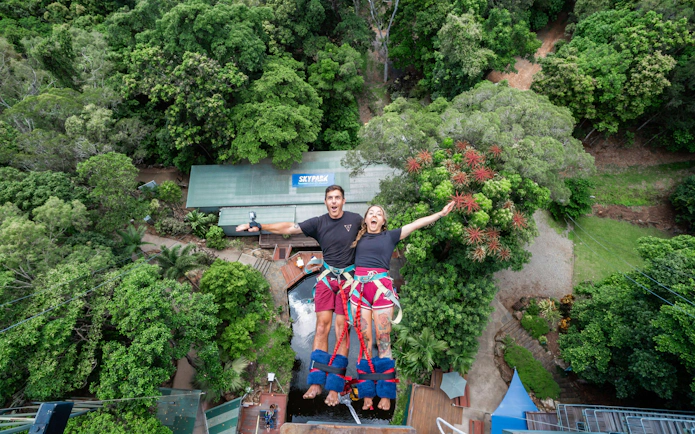 Visitors tandem back diving at Skypark Cairns amidst lush greenery.