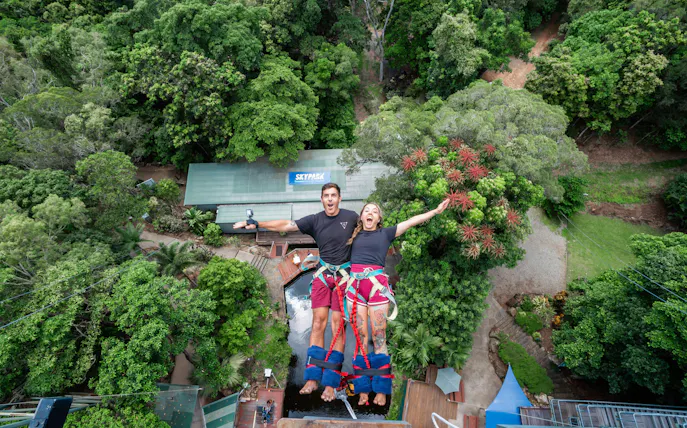 Visitors tandem back diving at Skypark Cairns amidst lush greenery.