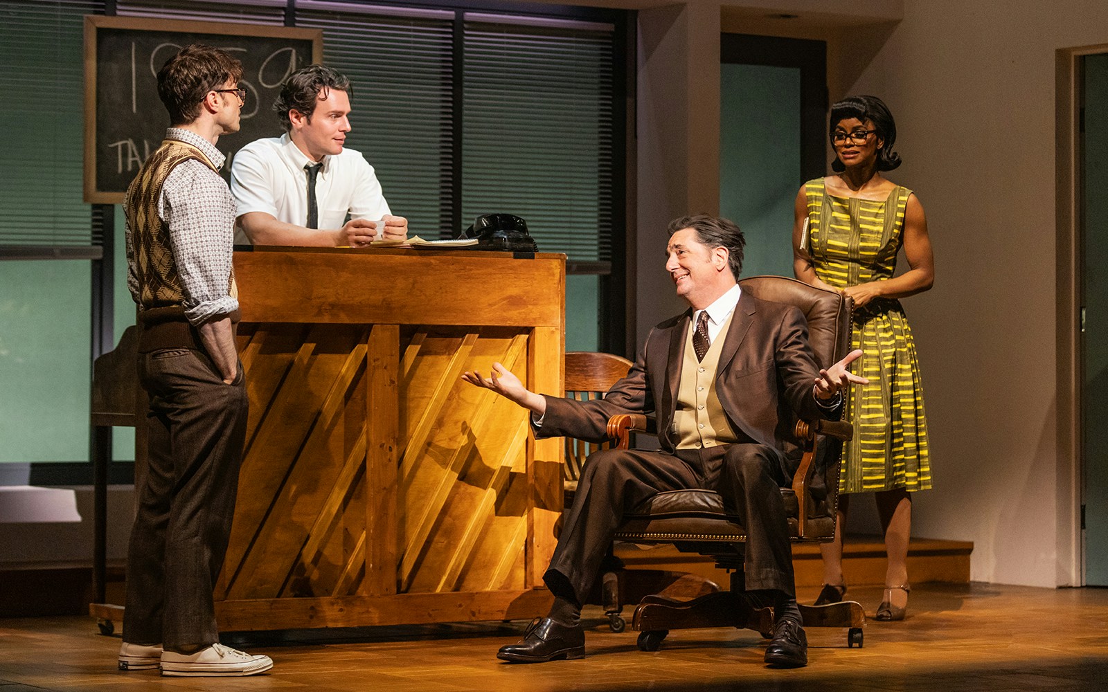 Four actors perform a scene from "Merrily We Roll Along" on stage.