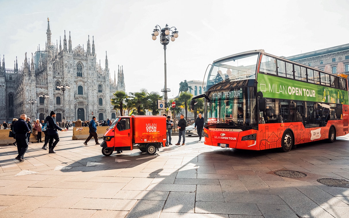 Milan Hop-on Hop-off bus near Duomo di Milano with tourists and cityscape.