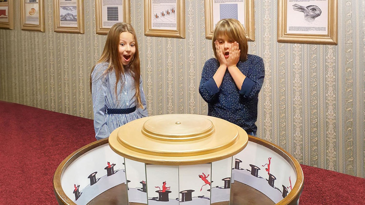 Guests reacting to optical illusion exhibit inside Museum of Fantastic Illusions.