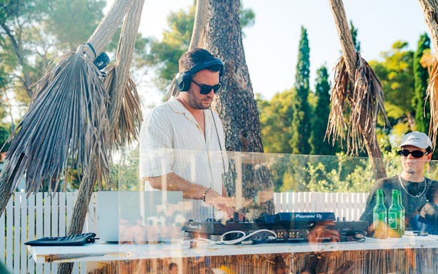 DJ performing at Sunset Boat Party in Split with palm trees in the background.