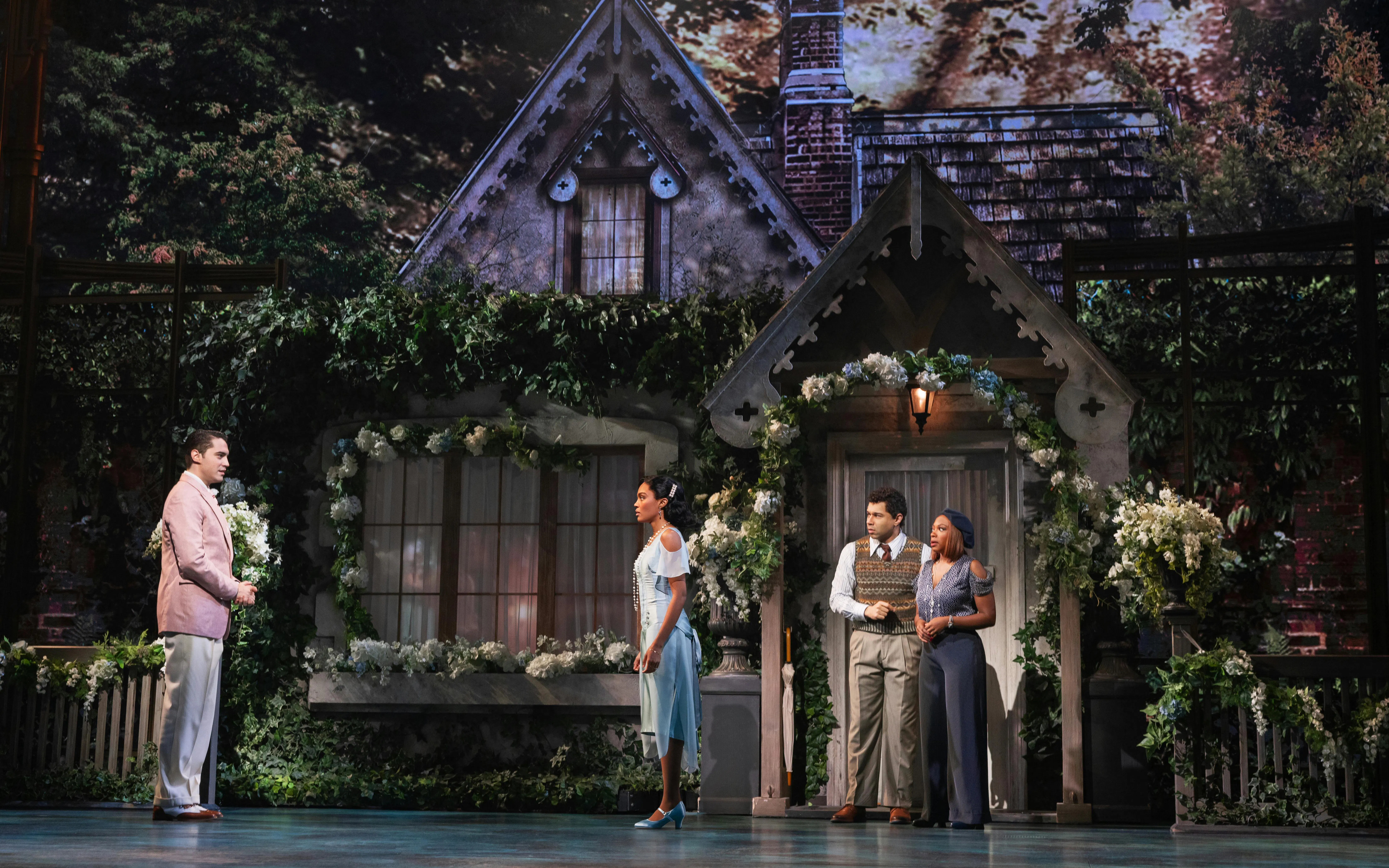 Broadway cast performing The Great Gatsby musical in front of a cottage set.