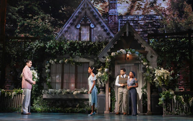 Broadway cast performing The Great Gatsby musical in front of a cottage set.