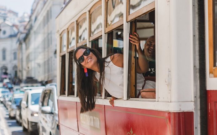 Passenger leaning out of Lisbon tram window on a city street.