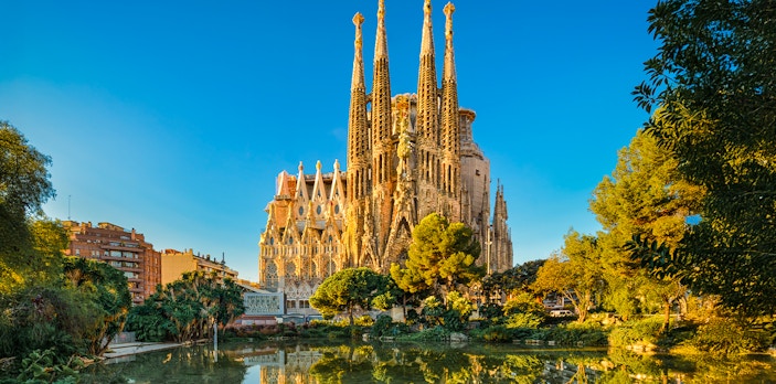 Sagrada Familia in Barcelona, Spain reflecting in a pond during golden hour.