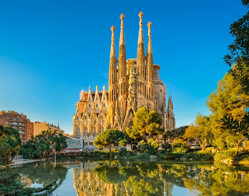 Sagrada Familia in Barcelona, Spain reflecting in a pond during golden hour.