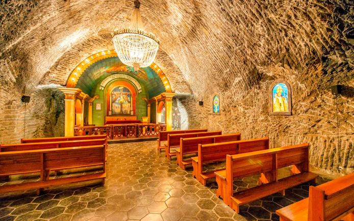 Chapel inside Wieliczka Salt Mine with wooden benches and ornate altar, Krakow, Poland.