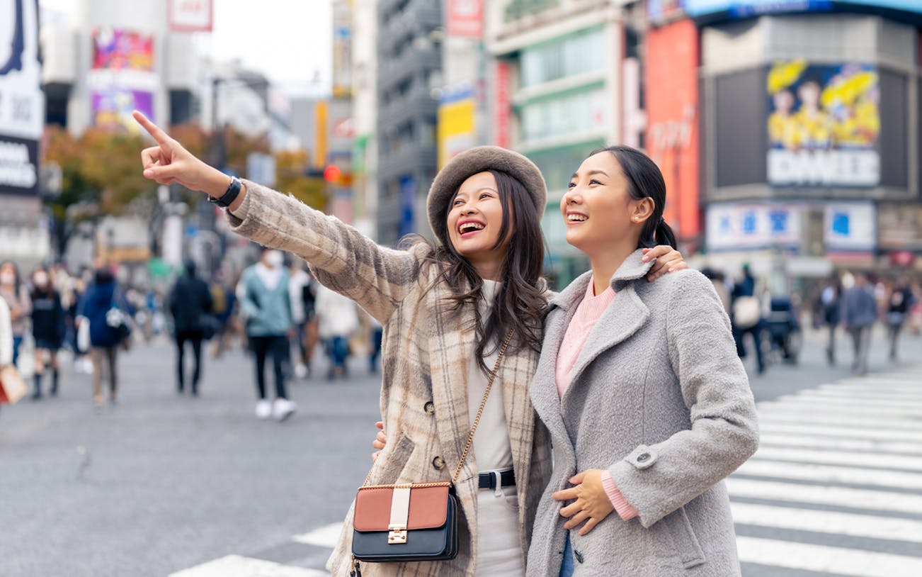 Two people enjoying a busy street in Japan during a 7-day guided tour.