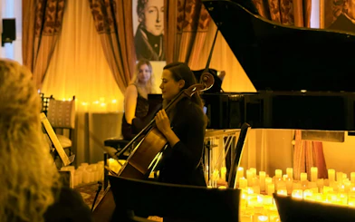 Cellist performing at candlelit Queen music concert, Chopin Gallery, Krakow.