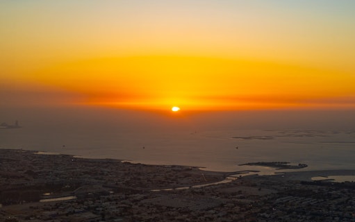 Sunrise view from Burj Khalifa Level 124 overlooking Dubai cityscape and coastline.