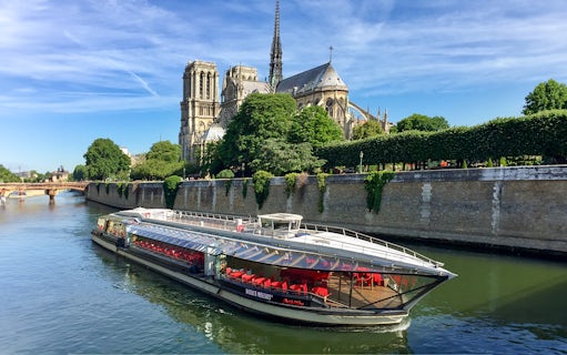 Tourists on Seine River cruise in Paris with Notre-Dame Cathedral view.