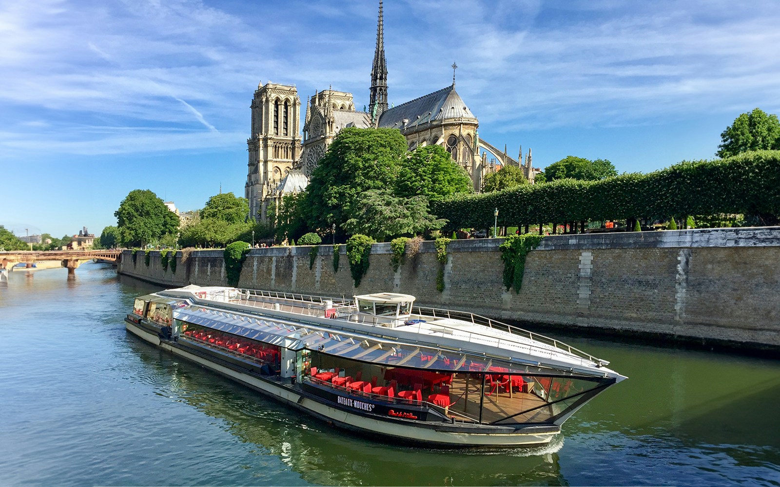 Tourists on Seine River cruise in Paris with Notre-Dame Cathedral view.