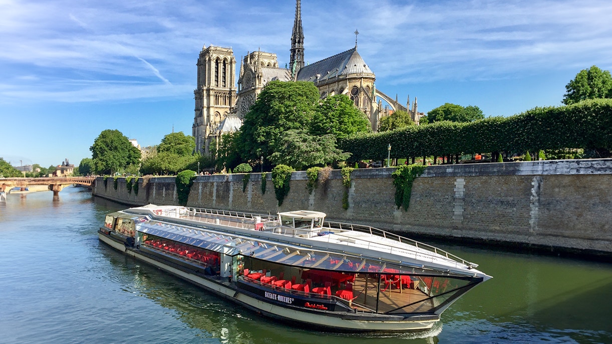 A river boat on Seine River departing with passengers onboard during evening.