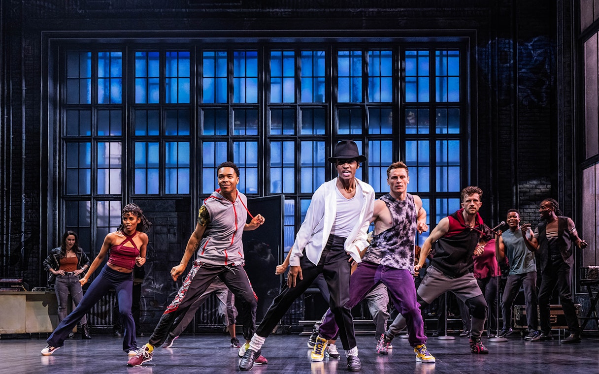 Performers dancing energetically on stage during MJ The Musical.