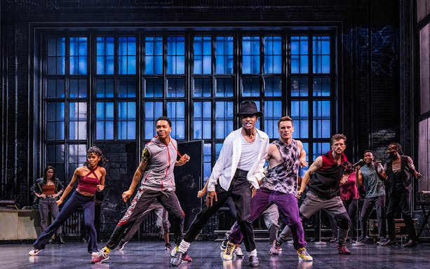 Performers dancing energetically on stage during MJ The Musical.