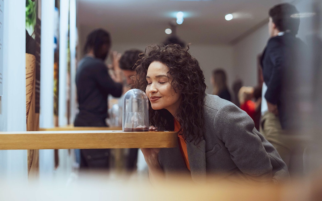 Woman enjoying chocolate aroma at The Chocolate Story Museum exhibit.