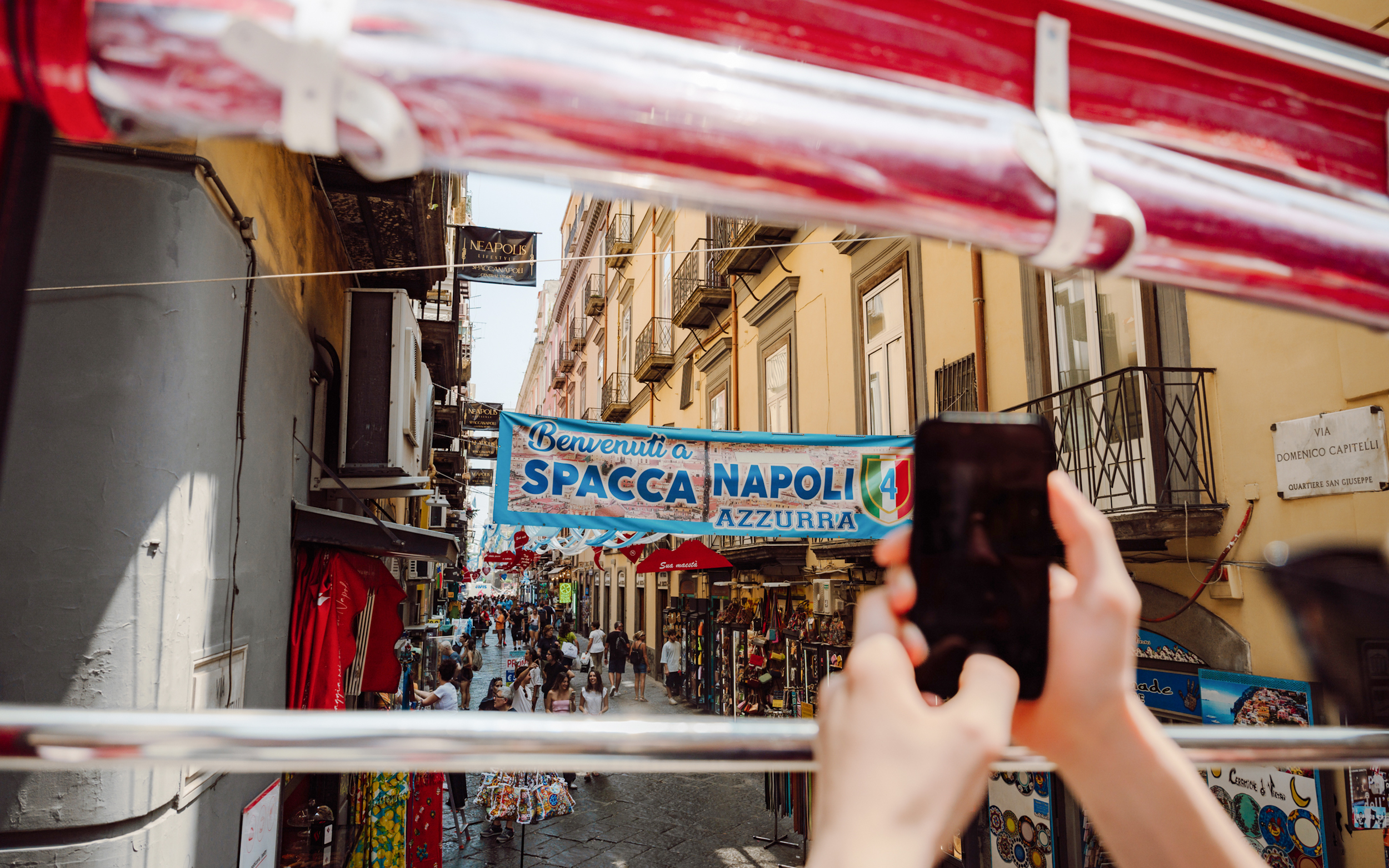 Naples street view from hop-on hop-off bus with Spaccanapoli banner.