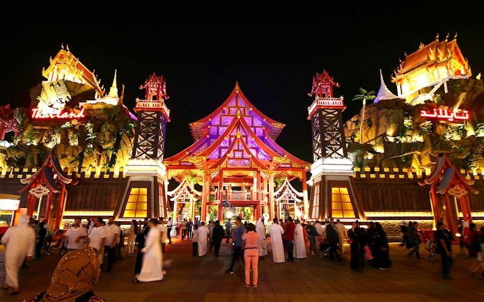 Tourists walking through the illuminated Thailand pavilion at Global Village Dubai.