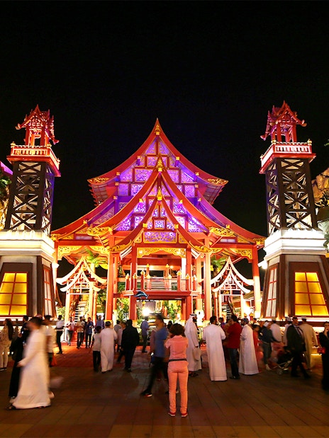 Tourists walking through the illuminated Thailand pavilion at Global Village Dubai.