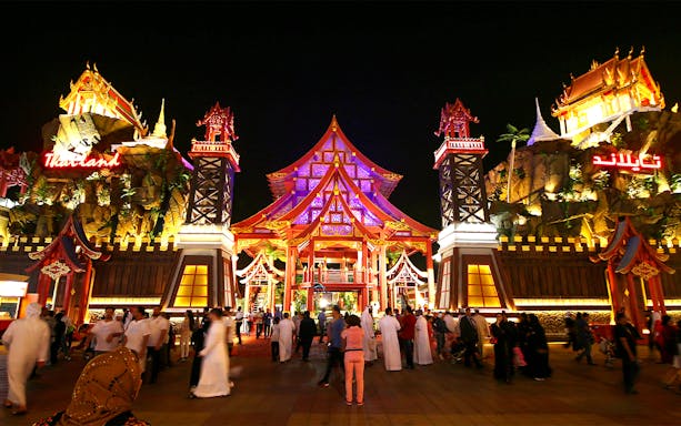 Tourists walking through the illuminated Thailand pavilion at Global Village Dubai.