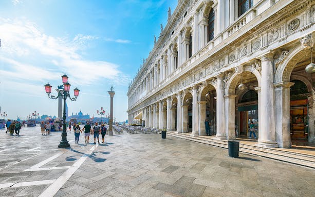 San Marco square in Venice with historic architecture and people walking.