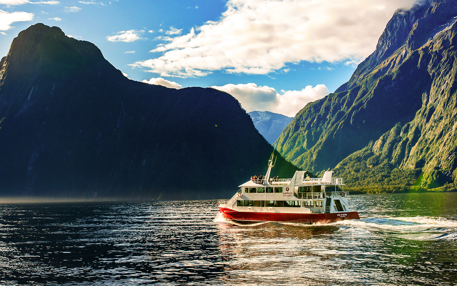 Cruise boat on Milford Sound with towering cliffs, Southern Discoveries tour.
