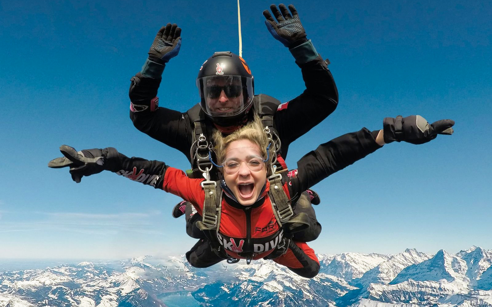 Skydiving tandem over snowy mountains in Interlaken, Switzerland.