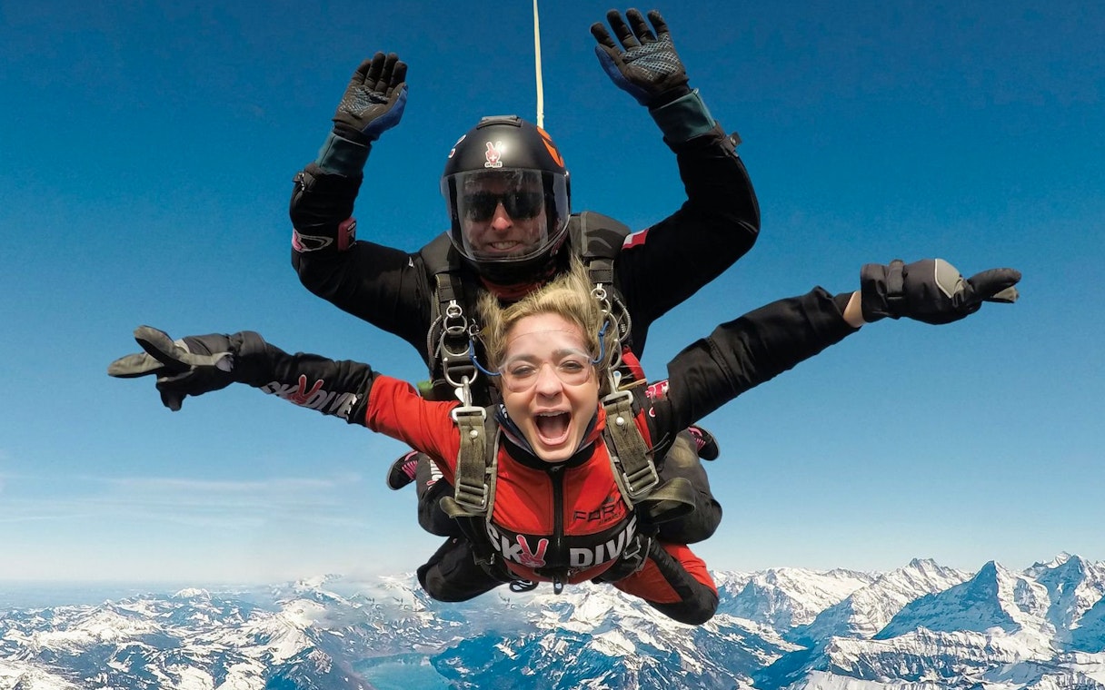 Skydiving tandem over snowy mountains in Interlaken, Switzerland.