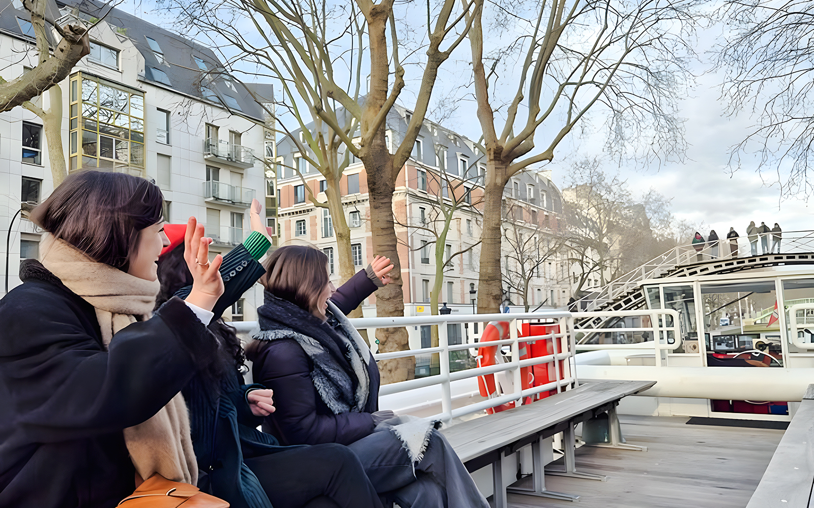 People waving from a boat on a Seine River canal cruise in Paris, France.