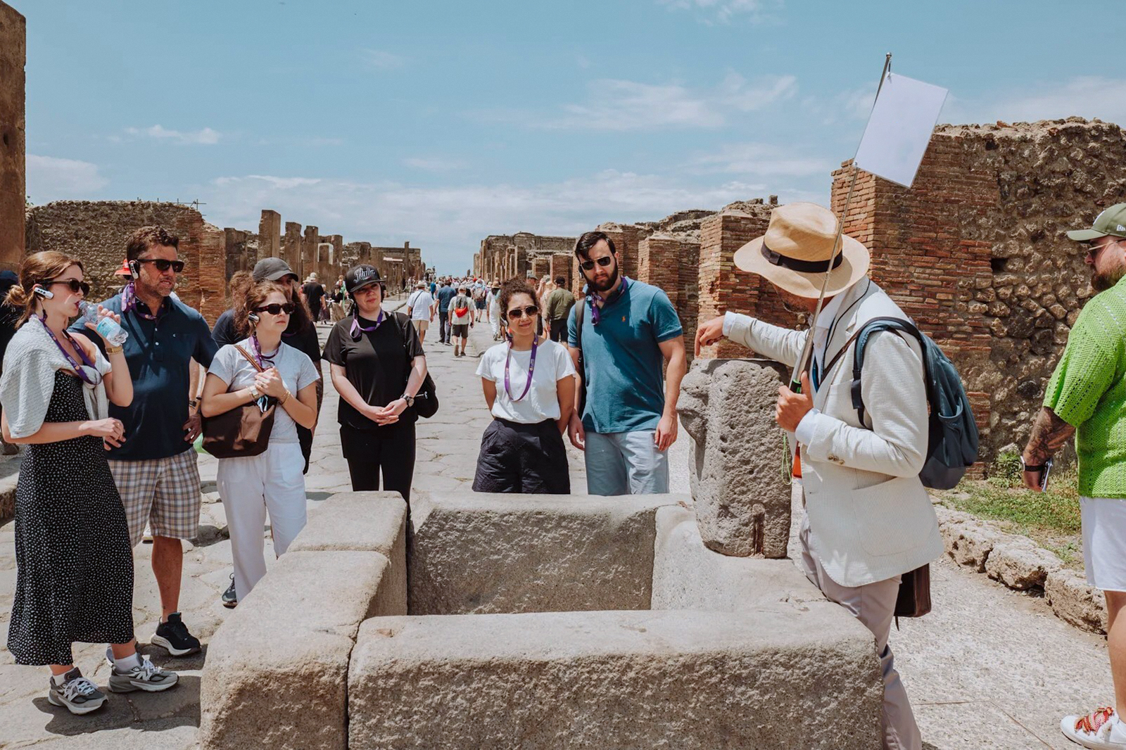 Visitors on a guided tour in Pompeii, exploring ancient ruins with a guide.