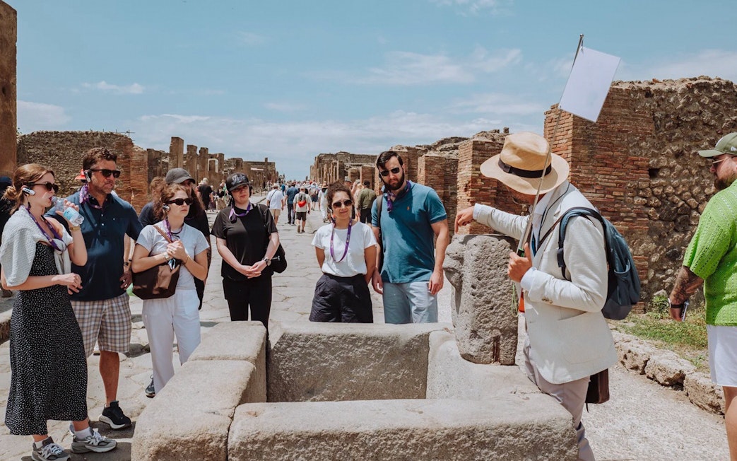 Visitors on a guided tour in Pompeii, exploring ancient ruins with a guide.