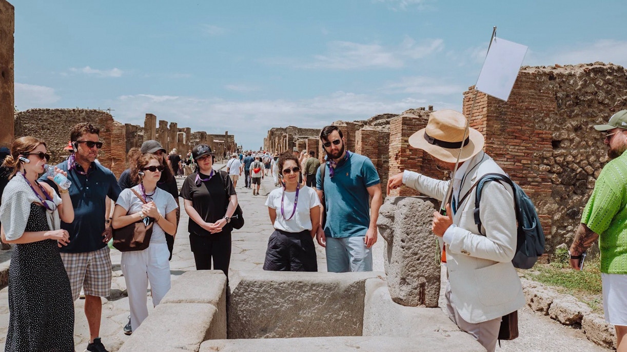 Visitors on a guided tour in Pompeii, exploring ancient ruins with a guide.