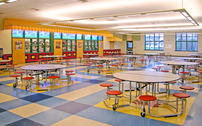 Colorful cafeteria with round tables and red stools at KidsSTOP Singapore.