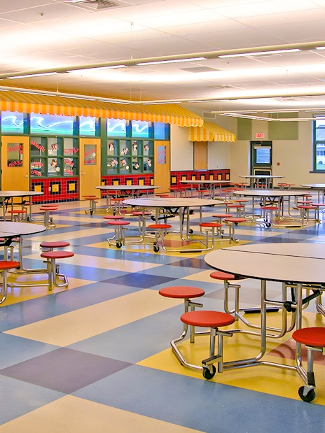 Colorful cafeteria with round tables and red stools at KidsSTOP Singapore.