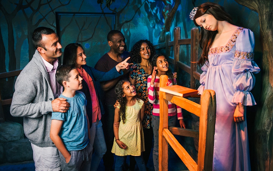 Group admiring Sleeping Beauty figure at a themed attraction.