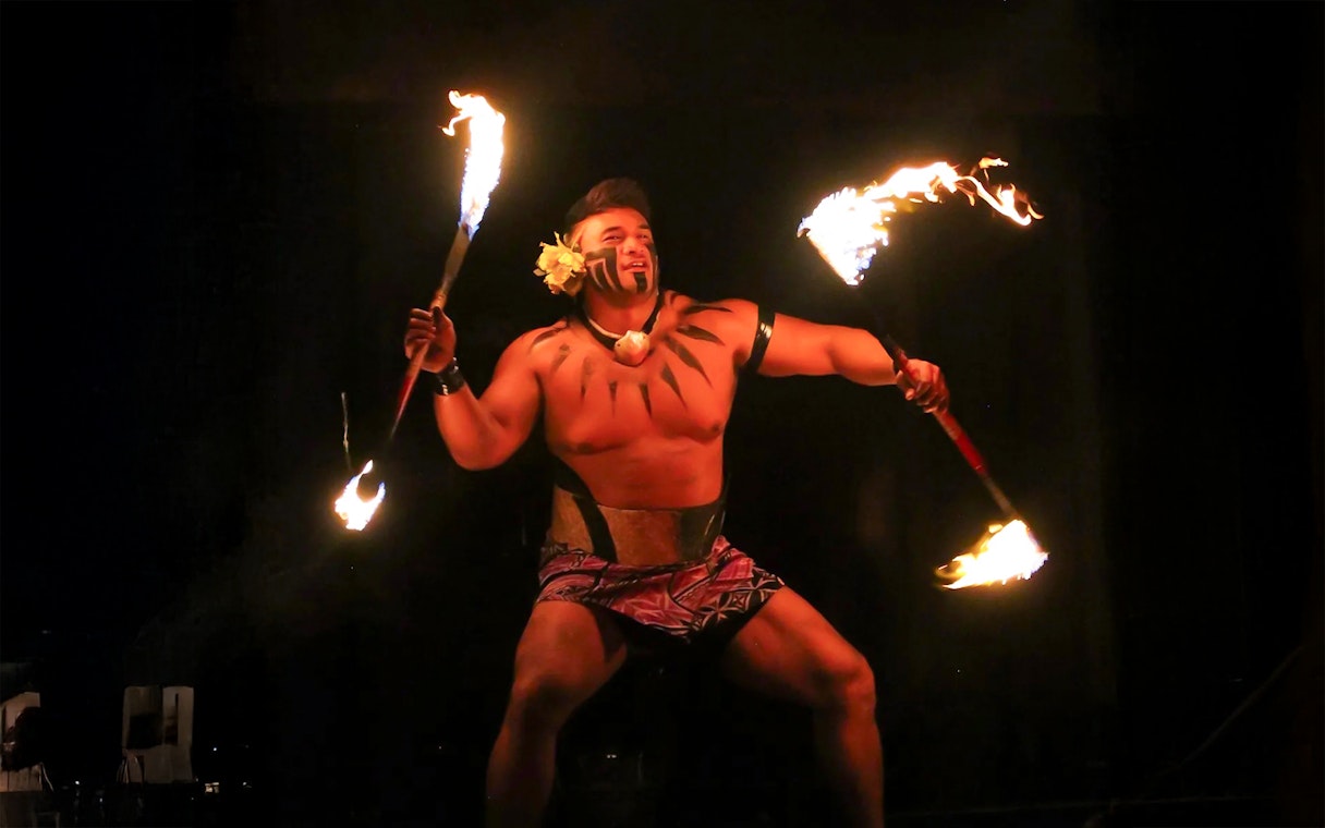 Fire dancer performing at Germaine's Luau with flaming torches.