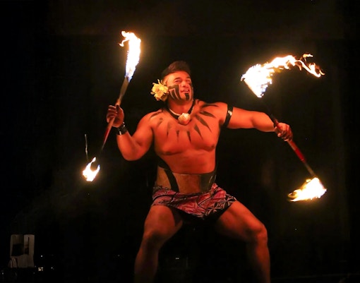 Fire dancer performing at Germaine's Luau with flaming torches.